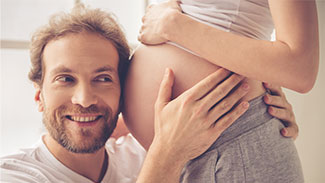 Mann hört Bauch seiner schwangeren Partnerin ab