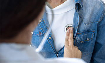 Ärztin hört Patientin mit Stethoskop ab Ärztin hört Patientin mit Stethoskop ab