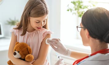 Ärztin tupft Kind Oberarm nach Impfung
